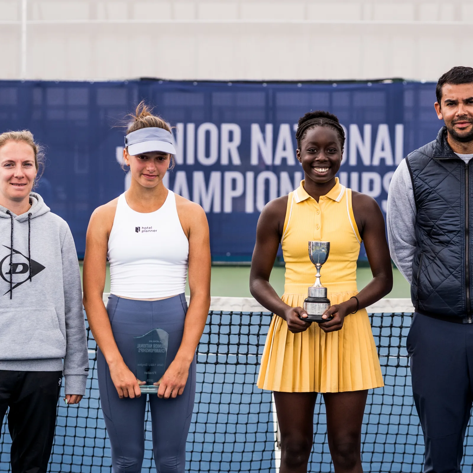 tennis participants pose for a picture with a trophy